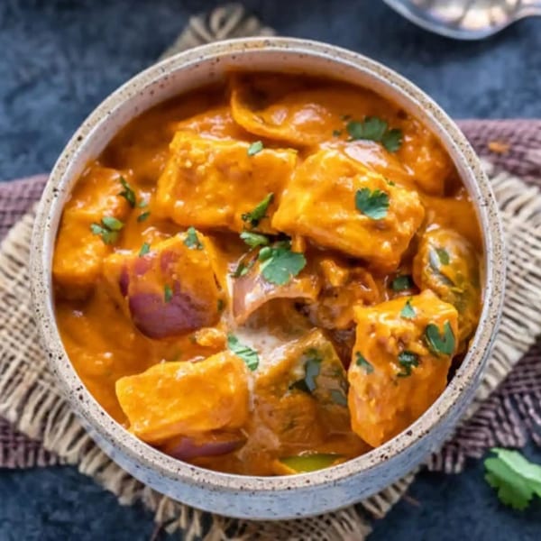 Tamarind Kitchen's paneer butter masala, a rich Indian curry with paneer, onions, and cilantro.
