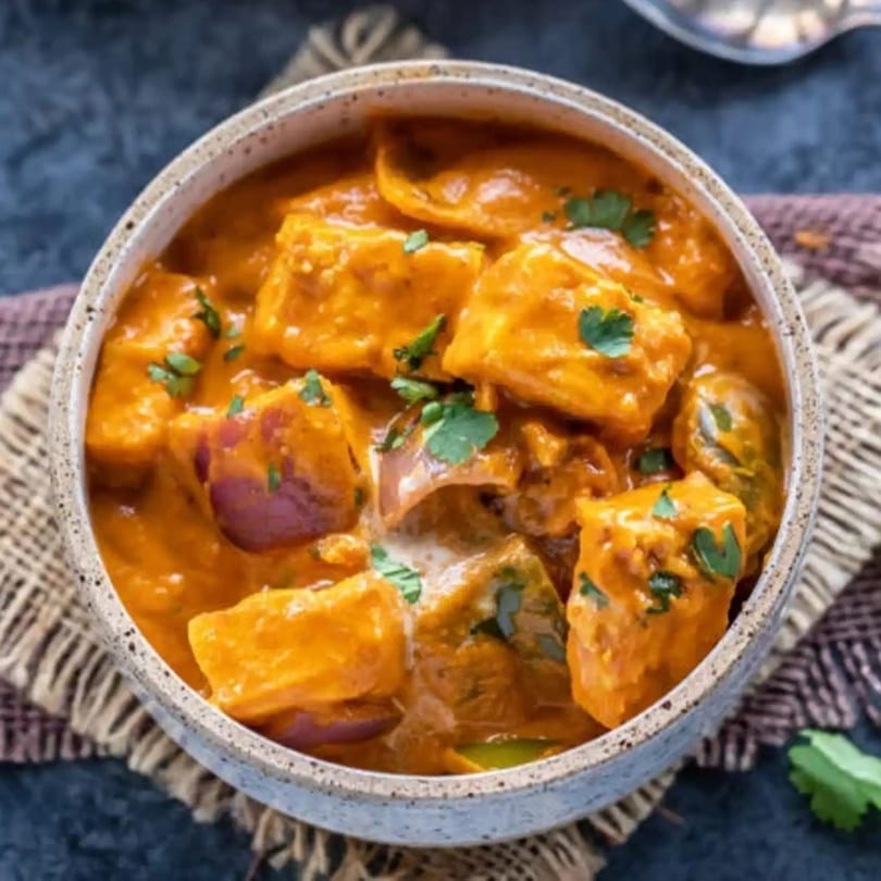 Tamarind Kitchen's paneer butter masala, a rich Indian curry with paneer, onions, and cilantro.