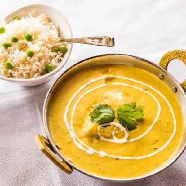 Tamarind Kitchen's yellow Indian curry with cream swirls and cilantro, served with pea rice.